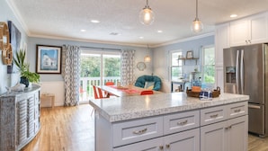 A modern kitchen with a central island, white cabinets, and a stainless steel refrigerator. - Casa Ola Escape (St. Augustine)