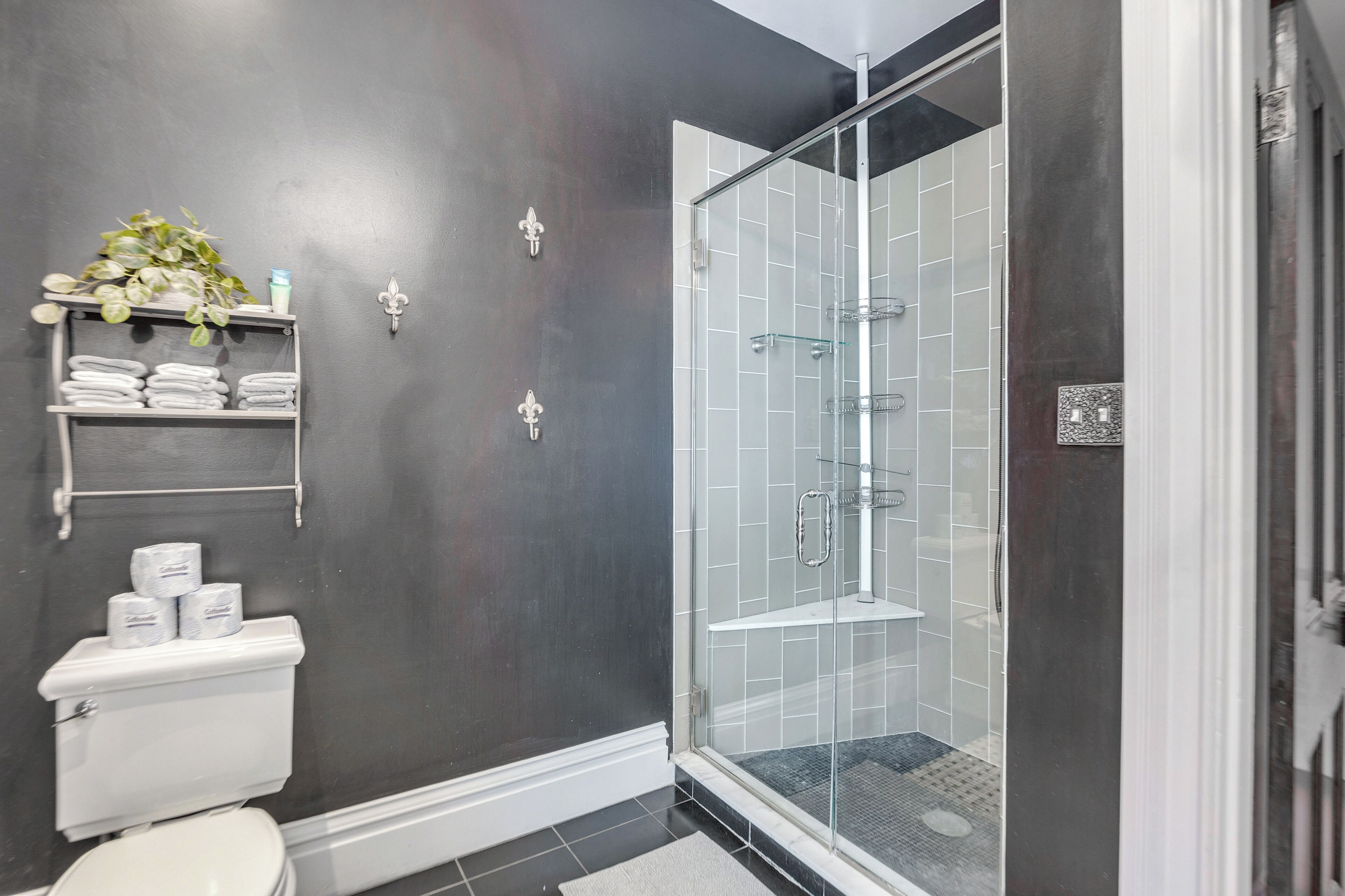 Een moderne badkamer met een douchecabine van glas, een toilet en een plank met handdoeken en toiletartikelen.