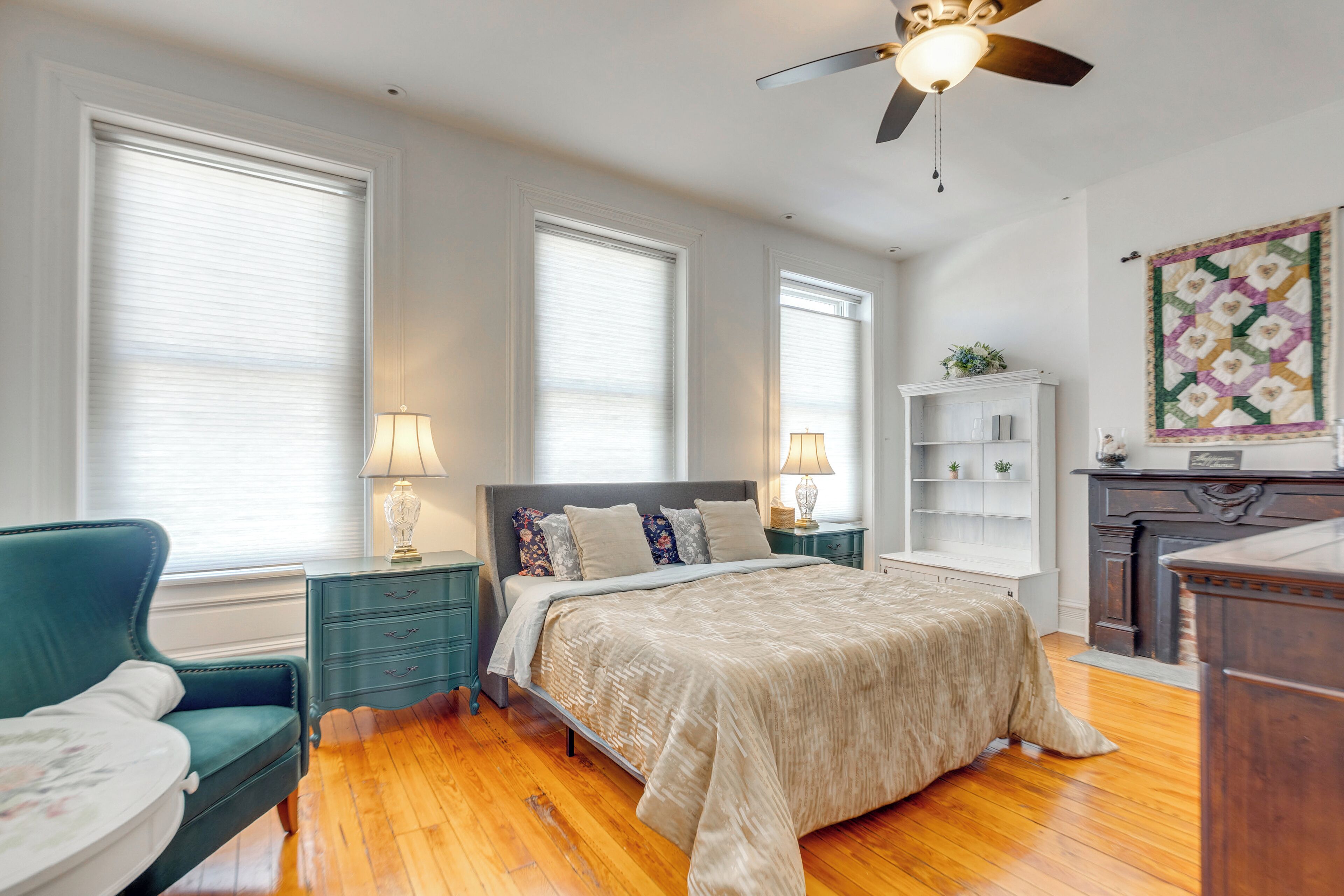 A bedroom with a bed, a chair, a nightstand, a dresser, and a ceiling fan.