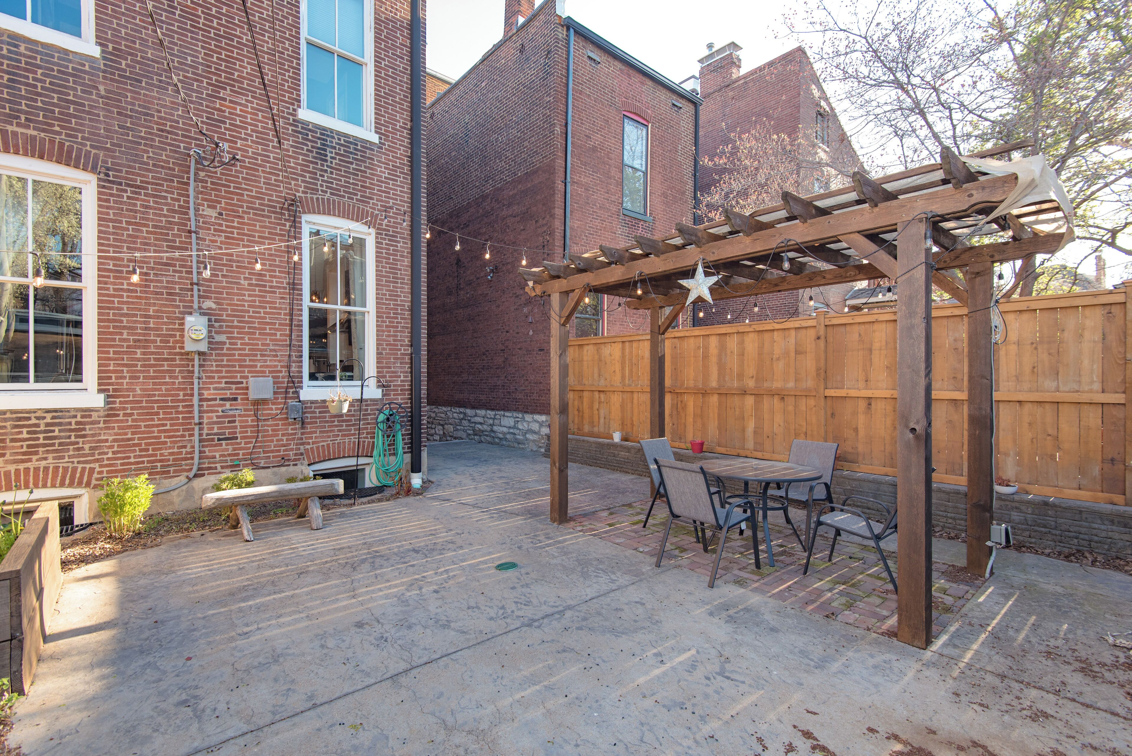 A backyard with a wooden pergola, a patio table, and chairs.