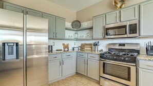 A kitchen with stainless steel appliances, light-colored cabinets, and a decorative rooster. - 5 Mi to Surprise Stadium: Chic Home w/ Pool (Surprise)
