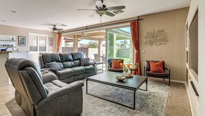 A living room with a leather sofa, a coffee table, and a ceiling fan. - 5 Mi to Surprise Stadium: Chic Home w/ Pool (Surprise)