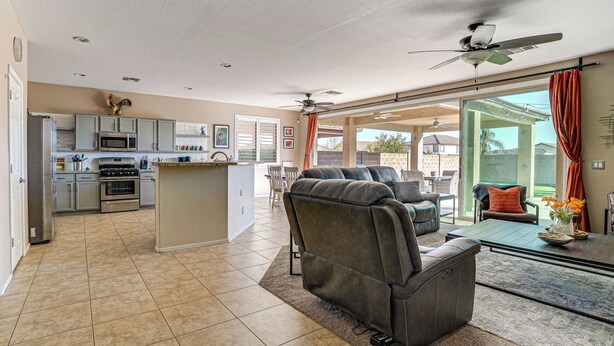 A spacious living area with a gray sofa, a glass coffee table, and a ceiling fan. - 5 Mi to Surprise Stadium: Chic Home w/ Pool (Surprise)
