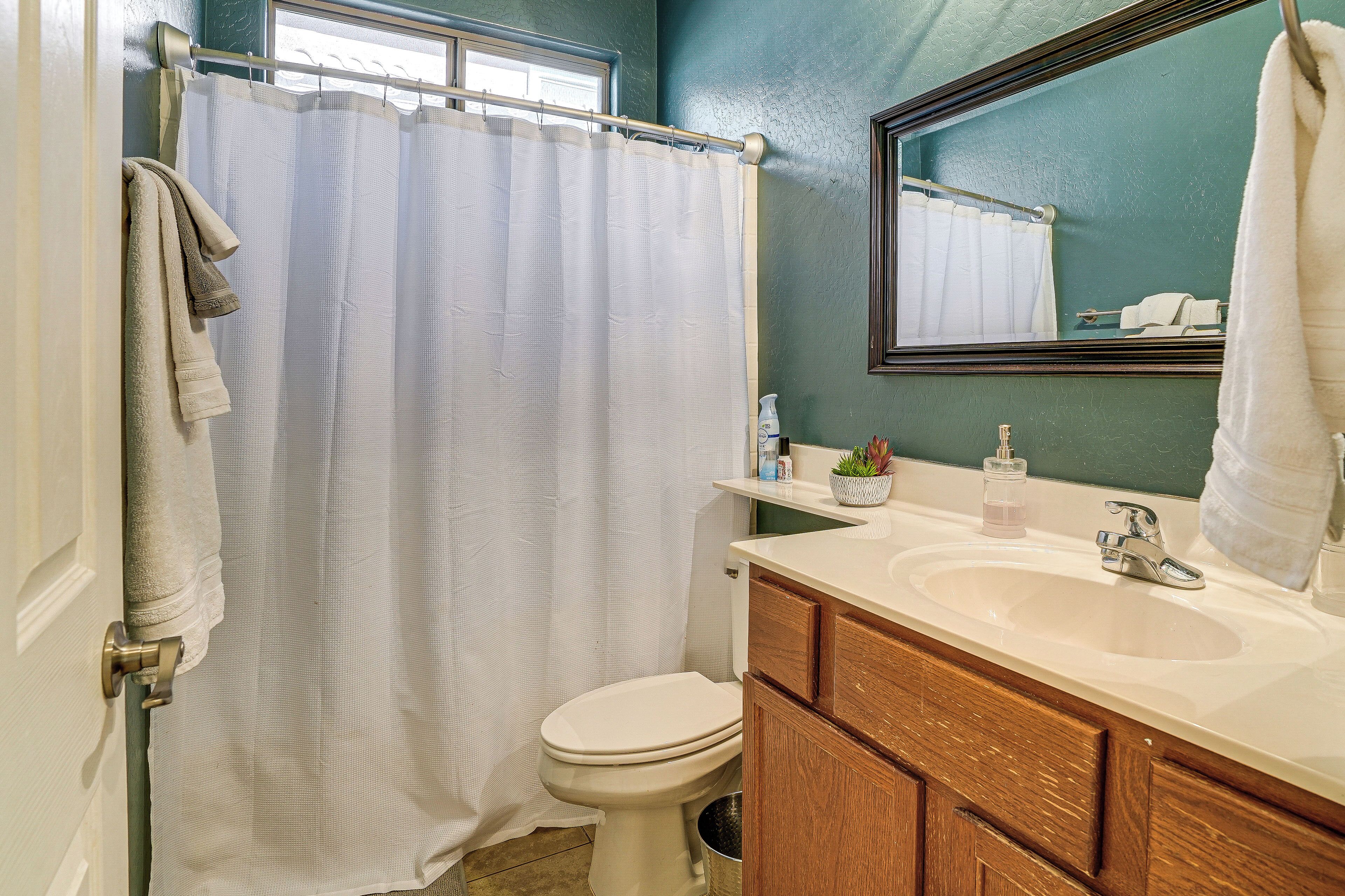 A bathroom with a white toilet, a beige sink, and a wooden vanity.