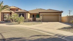 A residential house with a garage, a driveway, and a small garden with palm trees and shrubs. - 5 Mi to Surprise Stadium: Chic Home w/ Pool (Surprise)