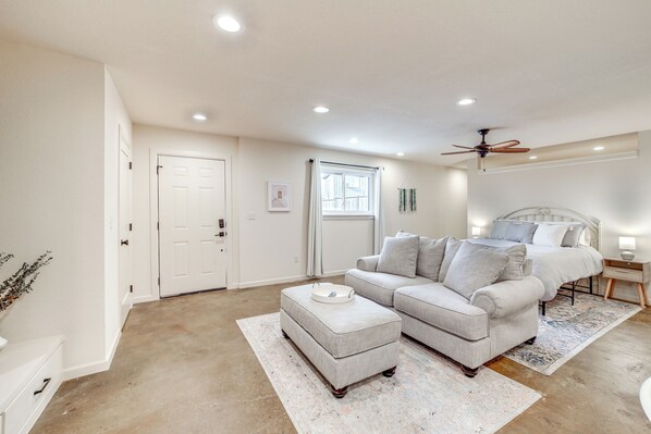 A bedroom with a bed, a nightstand, a ceiling fan, and a window with curtains. - Central & Modern Studio w/ Workspace in Owasso! (Owasso)