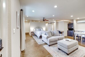 A spacious living area with a sofa, ottoman, and a ceiling fan. - Central & Modern Studio w/ Workspace in Owasso! (Owasso)