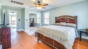 A bedroom with a wooden bed, a ceiling fan, and a view of the outside through a door. - Waterfront Home w/ Deck & Yard in Hampton! (Hampton)
