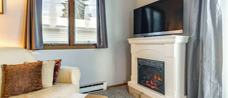 A living room with a white sofa, a fireplace, and a flat-screen TV mounted above it.