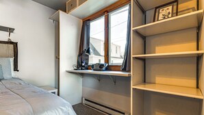 Une chambre à coucher comprenant un lit, un bureau avec un ordinateur, une fenêtre et des étagères intégrées.