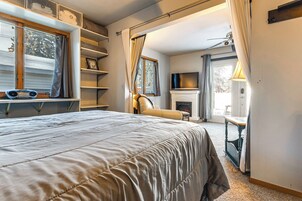 Un dormitorio con una cama grande, chimenea, televisor y ventana con cortinas.