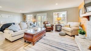 A spacious living room with a beige sofa, a wooden coffee table, and a fireplace. - Private Boat Dock: Troutman Home on the Water! (Troutman)