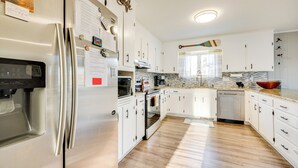 A modern kitchen with white cabinets, stainless steel appliances, and a wooden floor. - Private Boat Dock: Troutman Home on the Water! (Troutman)