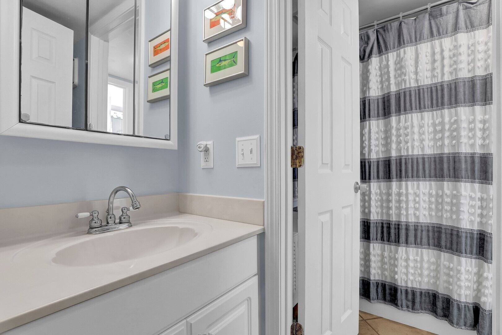 A bathroom with a white sink, a mirror, and a shower curtain.