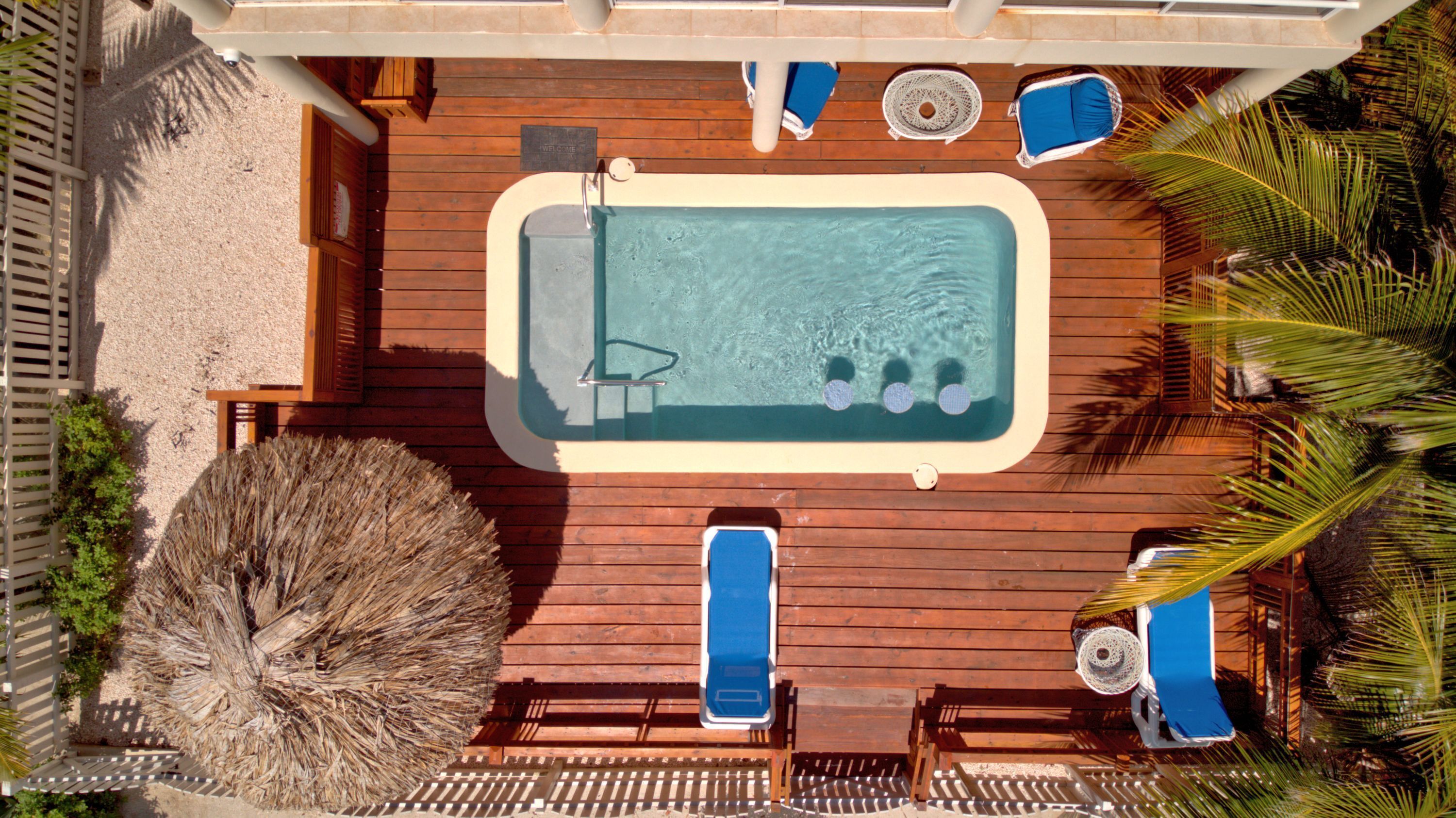 Ein Poolbereich auf dem Dach mit Whirlpool, Liegestühlen und einer Holzterrasse.