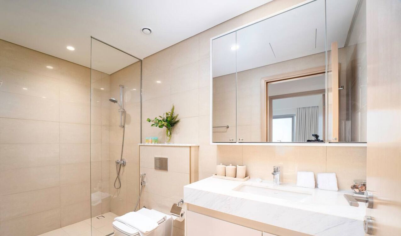 Un bagno moderno con cabina doccia in vetro, uno specchio grande e un mobile lavabo bianco con piano.
