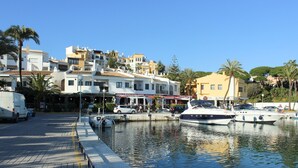 Un port de plaisance avec des bateaux amarrés, une promenade en bord de mer et des bâtiments abritant des commerces.
