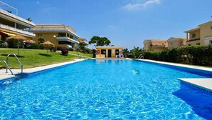 Une piscine d’un bleu éclatant, entourée d’immeubles dotés de balcons, avec une petite construction visible au loin.