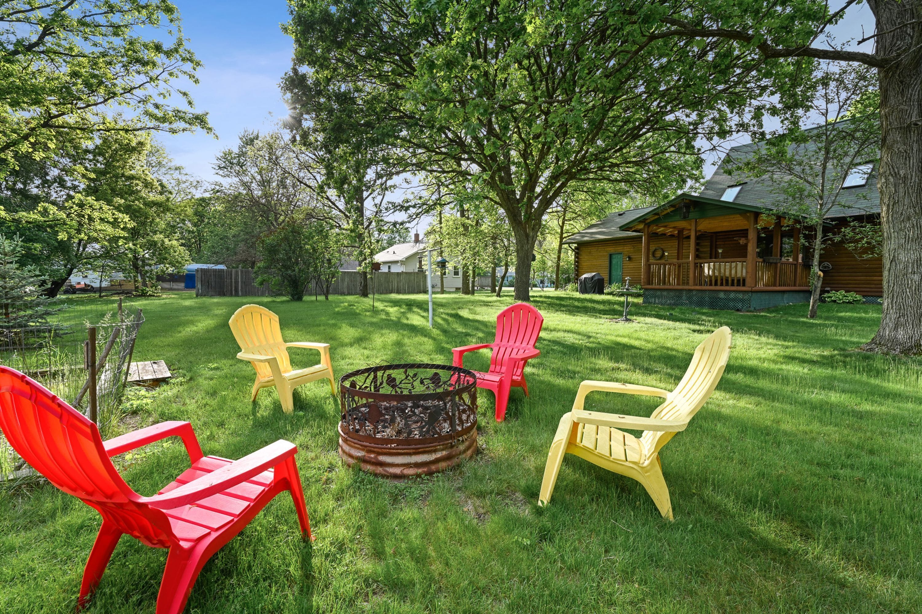 A backyard with a fire pit, outdoor chairs, and a wooden cabin.