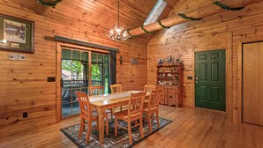 A wooden cabin interior with a dining area, a green door, and a view of the outdoors. - Wazeecha Lodge in Wisconsin Rapids (Wisconsin Rapids)