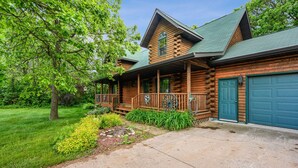 A log cabin with a porch, a garage, and a well-maintained lawn. - Wazeecha Lodge in Wisconsin Rapids (Wisconsin Rapids)