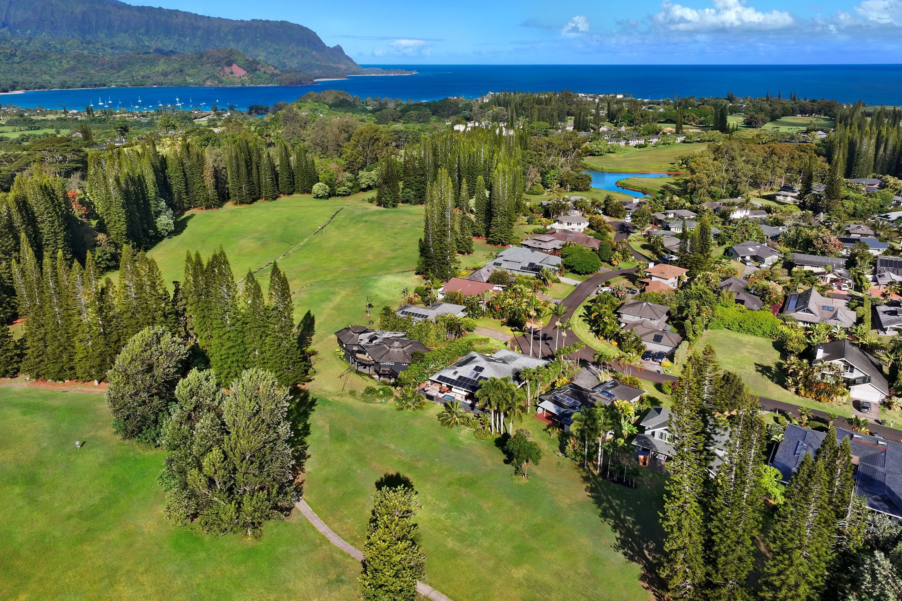 An aerial view of a residential area with houses, a golf course, and a coastline.