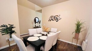 A dining area with a black table, white chairs, and a decorative wall piece. - Spacious 4BR Home w Game Room Office Backyard (Kyle)