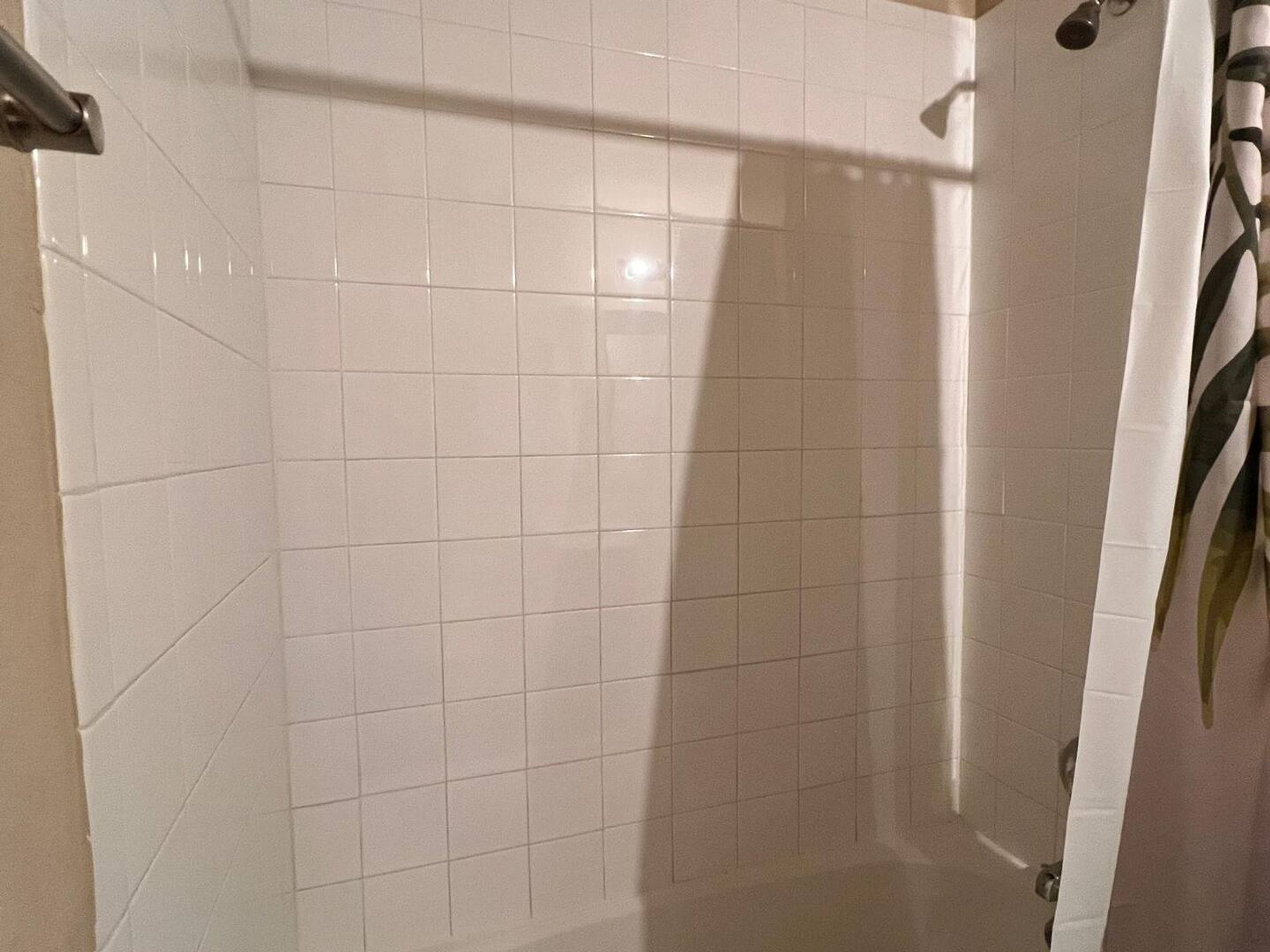 A bathroom with white tiled walls and a shower curtain.