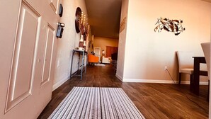 A hallway with a patterned rug, a dining area with chairs, and a wall-mounted sculpture. - Spacious 4BR Home w Game Room Office Backyard (Kyle)