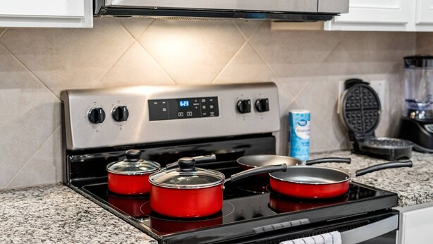 A kitchen with a stainless steel stove, red pots, a waffle maker, and a box of cereal. - Spacious Fort Worth House Ideal for Relocations (Fort Worth)