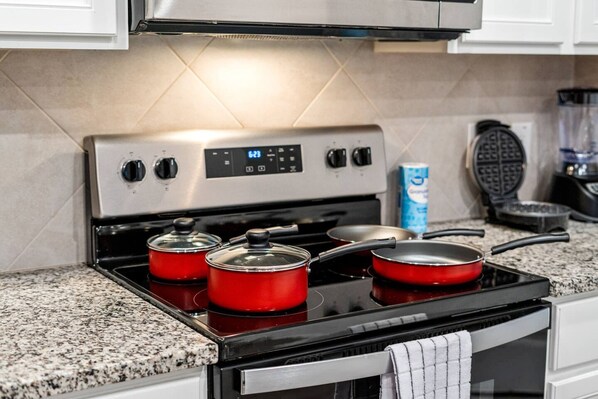 A kitchen with a stainless steel stove, red pots, a waffle maker, and a box of cereal. - Spacious Fort Worth House Ideal for Relocations (Fort Worth)