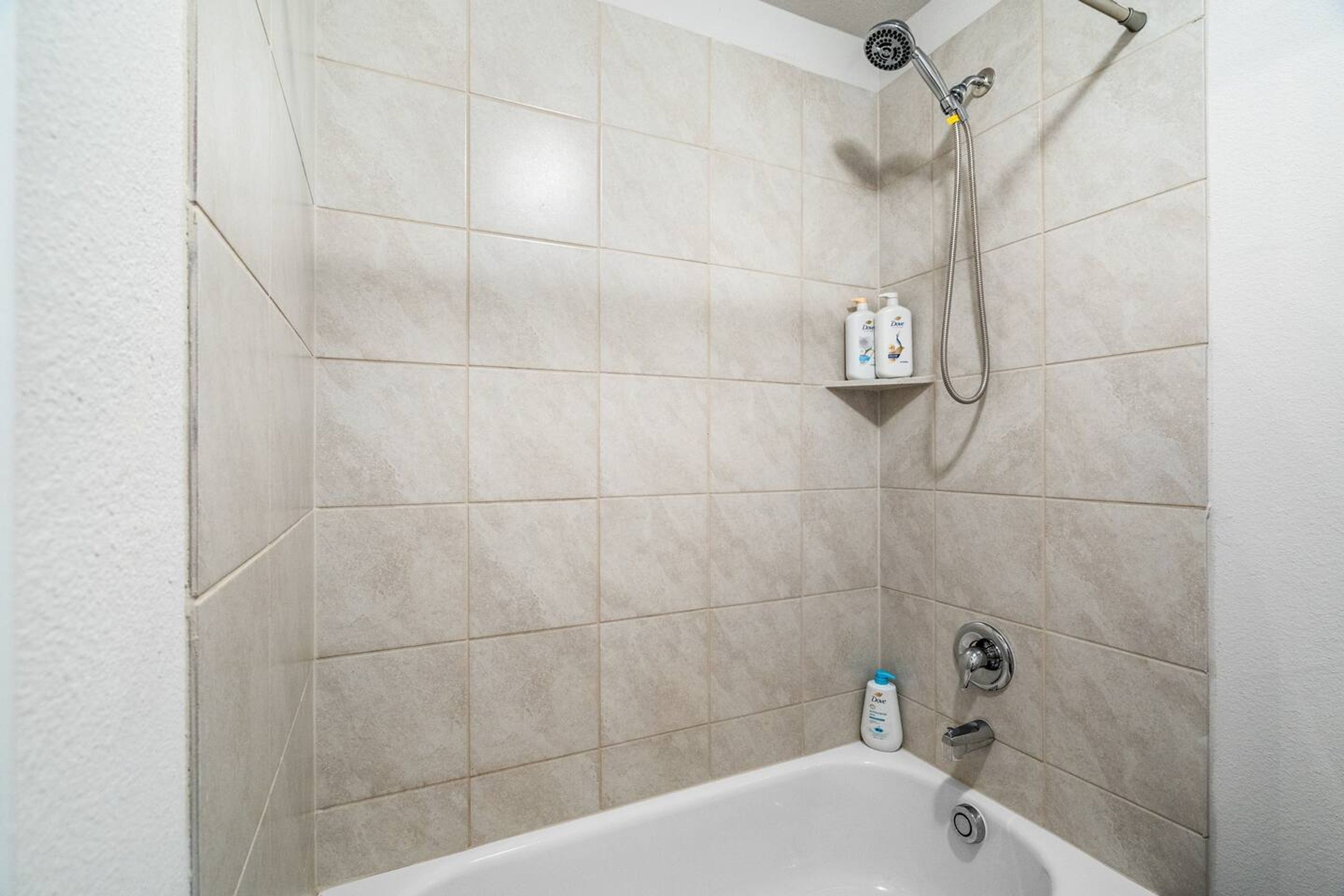 Une salle de bain équipée d’une baignoire, d’une douche et d’une étagère où sont rangés les articles de toilette.