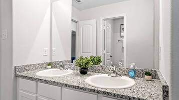 A bathroom with two sinks, granite countertops, a large mirror, and a potted plant.