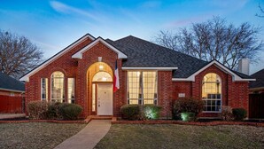 A brick house with a front entrance, a garage, and a well-maintained lawn. - Stylish One Level Home Ping Pong Foosball Yard (Frisco)