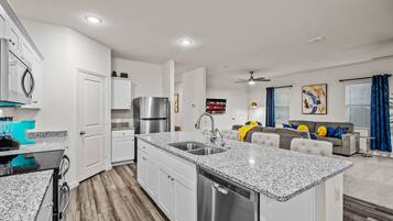 A modern kitchen with granite countertops, stainless steel appliances, and white cabinetry.
