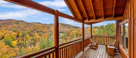 A wooden deck with a view of autumn foliage.