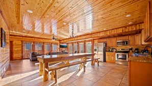 Une cuisine spacieuse avec des meubles de rangement en bois, une grande table en bois et un four encastré.