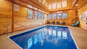 Une cabane en bois dotée d’une piscine, de murs en bois et d’un plafond avec des poutres apparentes.