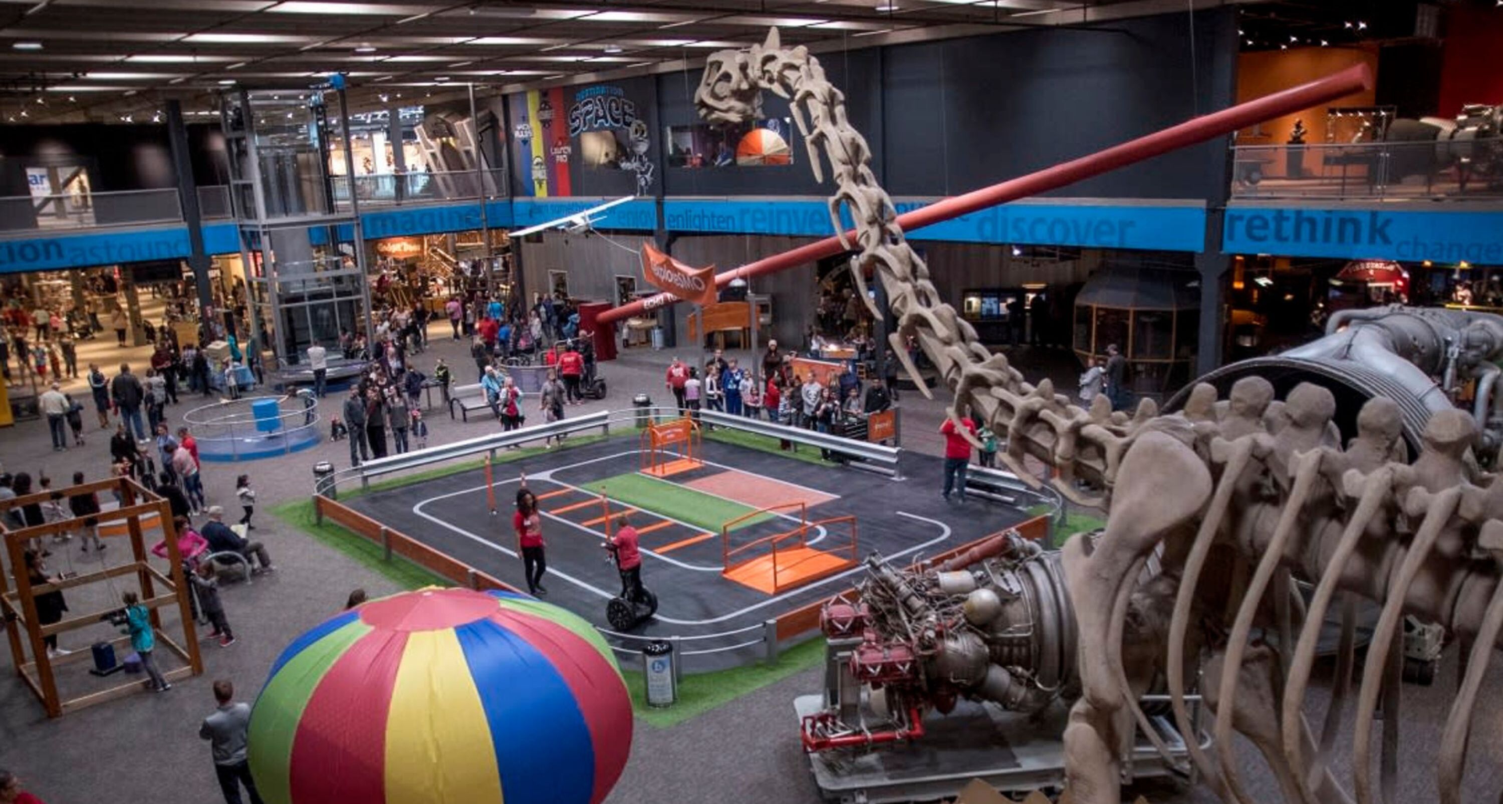 A spacious indoor area with a large dinosaur skeleton, a colorful ball pit, and a children's play area.