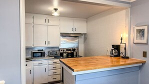 A compact kitchen with white cabinets, a wooden countertop, and a coffee maker. - Affordable 2BR Getaway Near Plaza District Lilac1 (Midwest City)