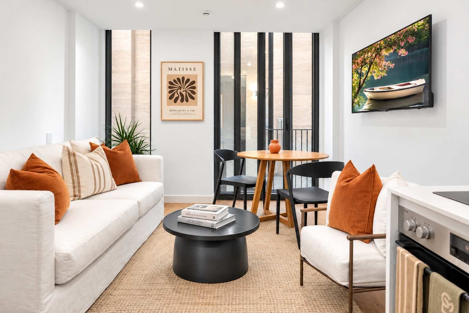 A modern living room with a sofa, coffee table, and a dining area with chairs and a table.