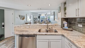 A modern kitchen with granite countertops, stainless steel appliances, and white cabinetry. - Wonderfully Updated Two Bedroom Condominium! (Hilton Head Island)