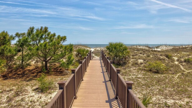 A wooden boardwalk leading to a beach with dunes and sparse vegetation. - Wonderfully Updated Two Bedroom Condominium! (Hilton Head Island)