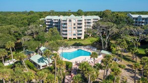 A resort with a central pool, surrounded by palm trees and a large building with multiple balconies. - Wonderfully Updated Two Bedroom Condominium! (Hilton Head Island)