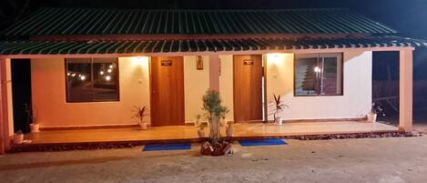 Un edificio de dos pisos con techo de tejas, una recepción y un cartel que indica una habitación de huéspedes.