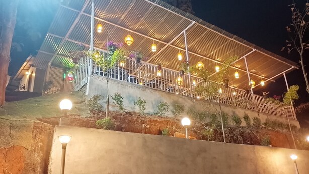 A building with a covered outdoor area, railings, and multiple light fixtures. - HIYAS RETREAT (Sonapur)
