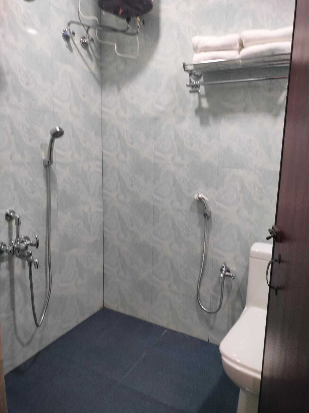 A bathroom with a shower, toilet, and towel rack.