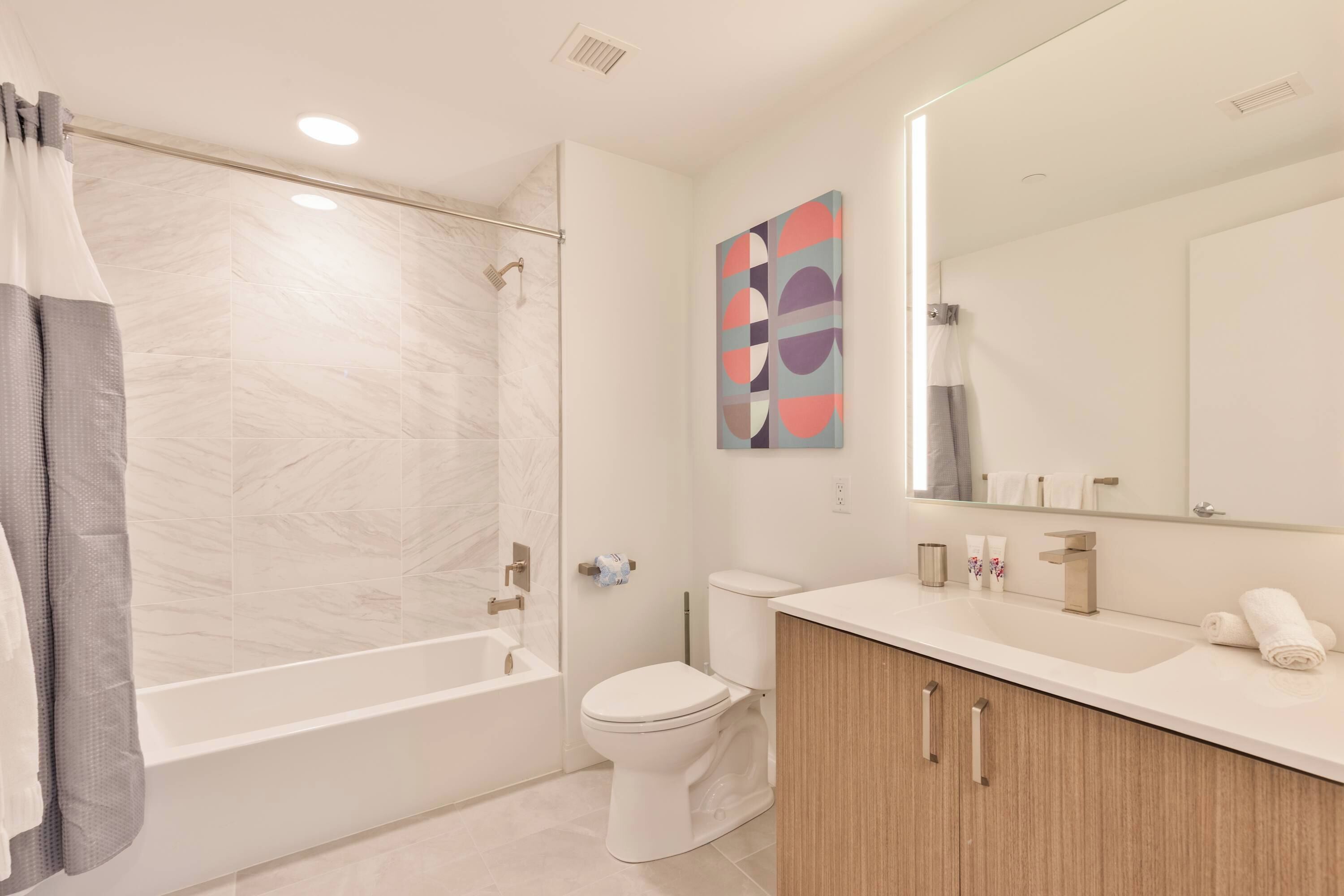 A modern bathroom with a bathtub, toilet, and vanity.