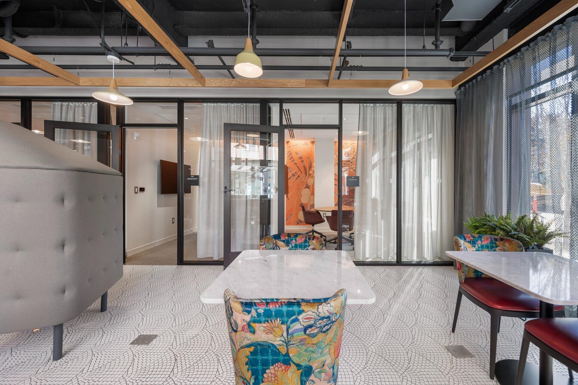 A modern office space with a large meeting table, comfortable seating, and a view of the city through large windows.