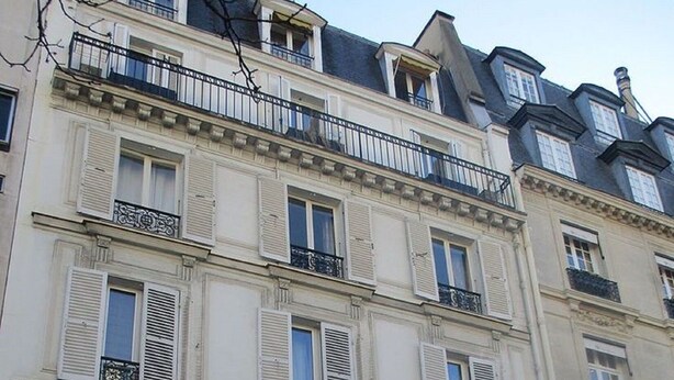 Un edificio a più piani con uno stile architettonico classico, caratterizzato da facciate bianche, persiane e balconi.